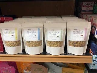Four Mary's All Natural granola pouches lined up on a retail shelf.